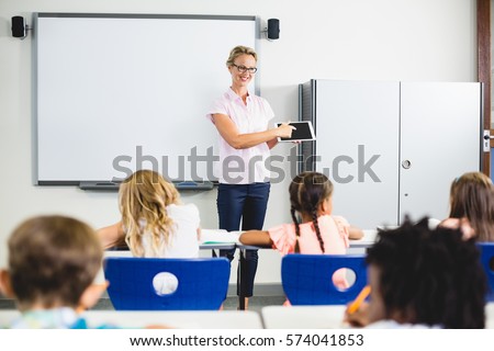 Teacher teaching kids on digital tablet in classroom at school