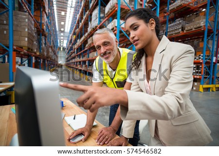 Manager and worker are looking a computer in a warehouse