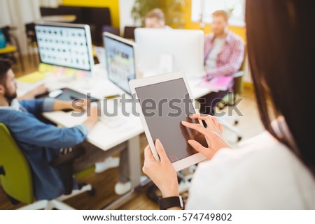 Rear view of young female executive using digital tablet at creative office