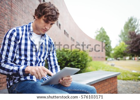 Student using digital tablet in college campus