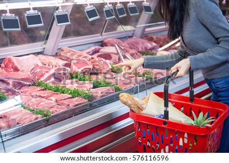 Mid section of woman pointing at meat in display at supermarket