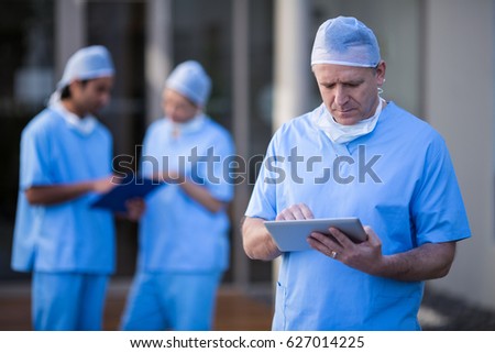 Male surgeon using digital tablet at hospital