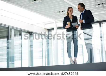 Business colleagues interacting with each other in office corridor