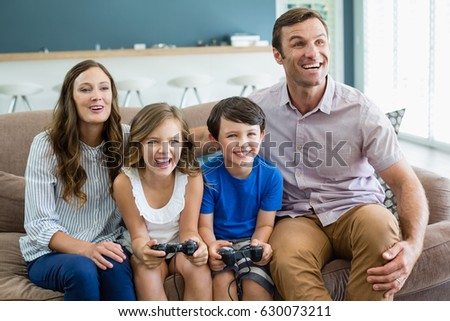 Happy family playing video games together in living room at home