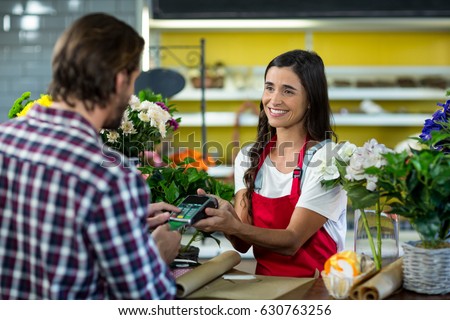 Florist receiving a payment by credit card from the customer in the florist shop
