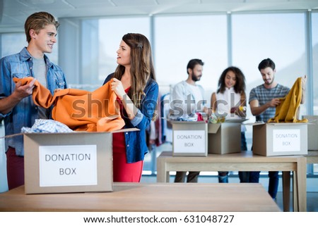 Creative business team sorting clothes in donation box in office