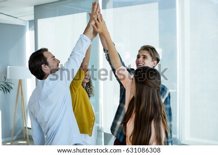 Creative business team giving a high five to each other in office