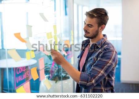 Close up of man reading sticky notes on the glass wall in office