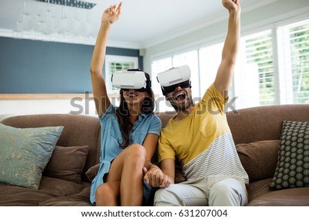 Couple using virtual reality headset in living room at home