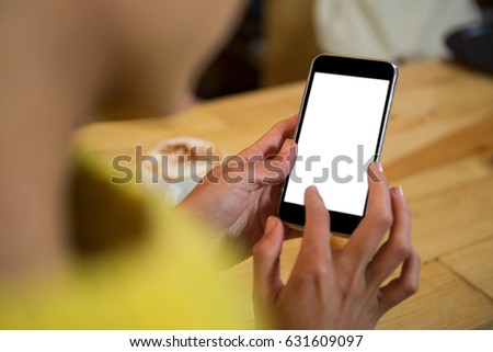 Cropped image of woman using mobile phone at table in coffee shop