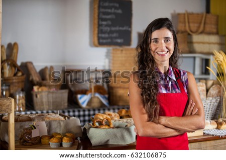 Portrait of female staff standing with hands crossed in supermarket