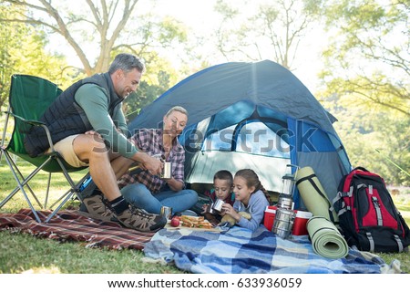 Family having snacks and coffee outside the tent at campsite