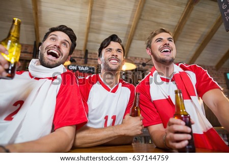 Cheerful friends holding beer bottles in pub