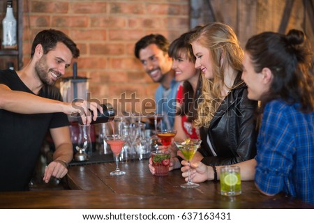 Smiling bartender serving drink for customers in pub