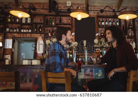 Friends having beer at bar counter in pub