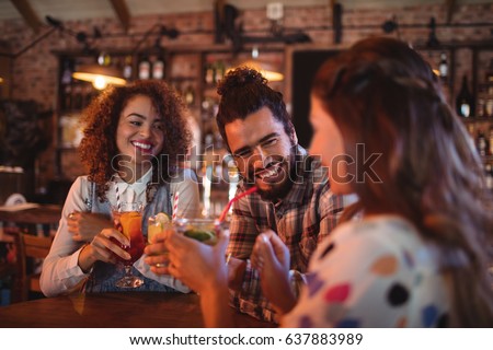 Close up of young friends interacting with each other having drinks in pub