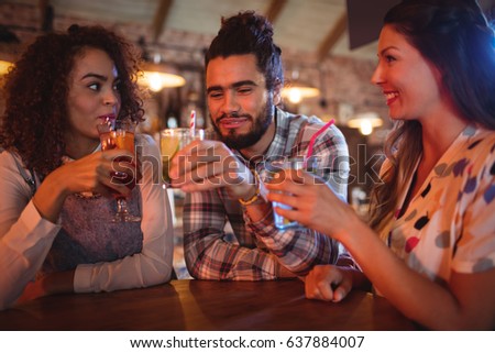 Young friends interacting with each other having drinks in pub