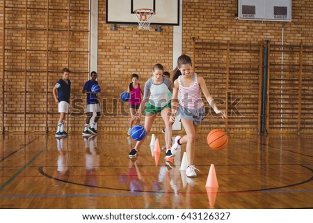 High school kids practicing football using cones for dribbling drill in the court