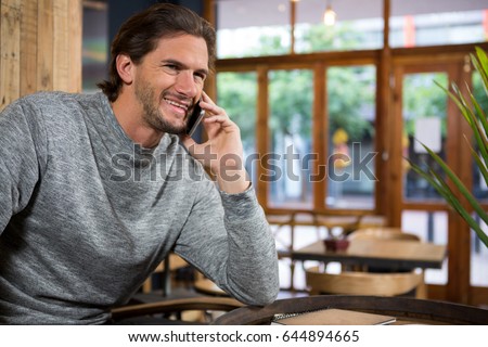 Smiling man talking on smart phone in coffee shop