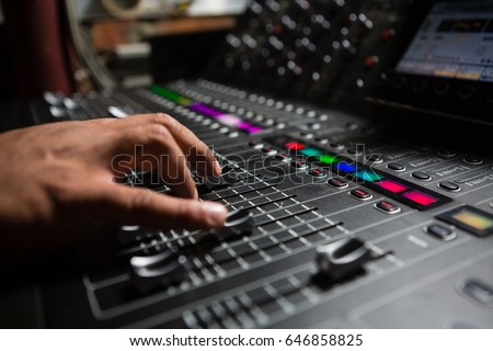 Hand of male audio engineer using sound mixer in recording studio