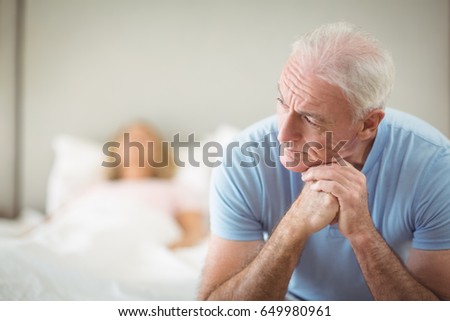 Worried senior man sitting in bedroom at home