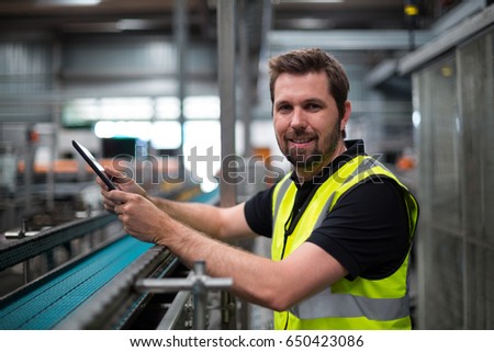 Portrait of smiling factory worker using a digital tablet in factory
