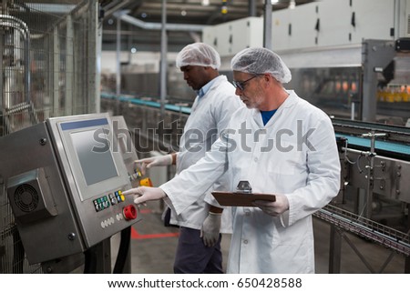 Two factory engineer operating machine in drinks production plant