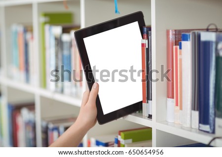 Hand of student keeping digital tablet in bookshelf in library at school