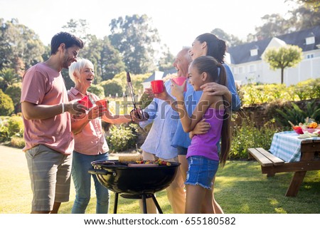 Happy family laughing and talking while preparing barbecue in the park