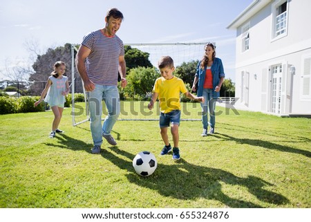Happy family playing football in the park on a sunny day