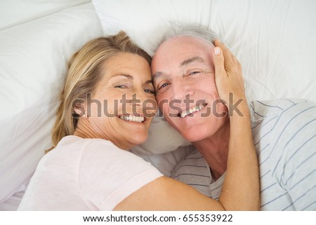 Portrait of happy senior couple embracing on bed in bed room