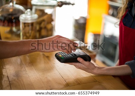 Man paying bill through smartphone using NFC technology in cafe