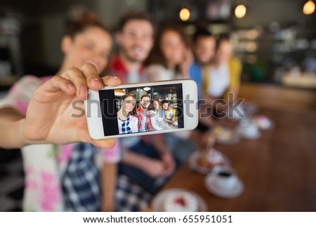 Friends taking photo through mobile phone in pub