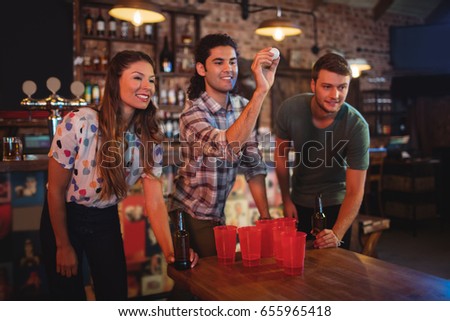 Group of happy friends playing game in pub