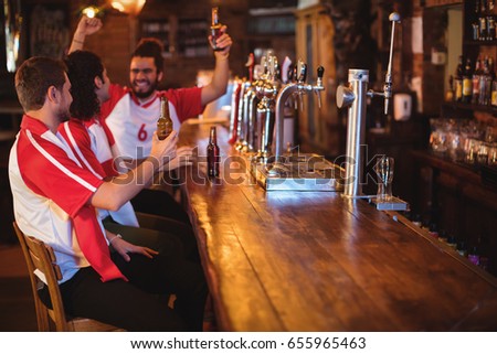 Group of male friends watching football match in pub