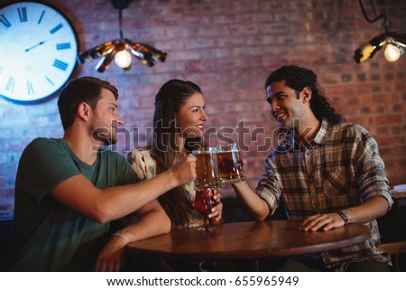 Young friends toasting beer mugs in pub
