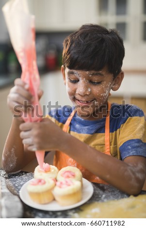 Boy making cup cakes in kitchen at home
