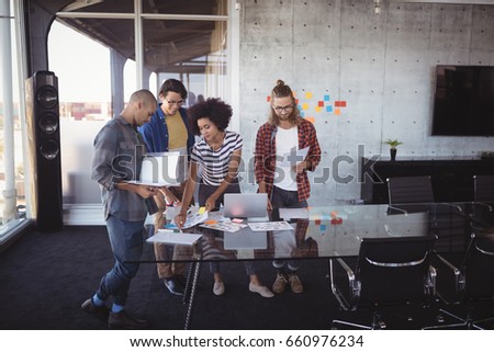 Colleagues discussing ideas while standing in creative office