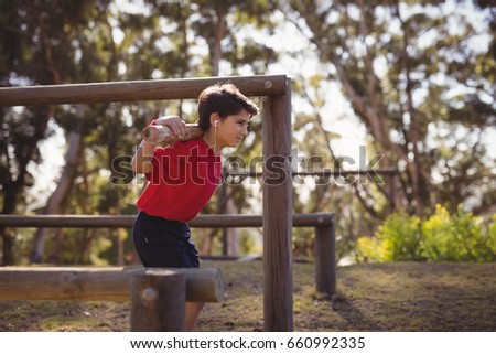 Happy boy exercising with log while listening music during obstacle course in boot camp