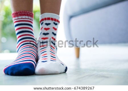 Low section of girl wearing patterned socks while standing at home
