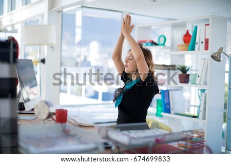 Female executive doing yoga on desk in office