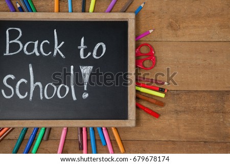 Overhead view of text written on slate surrounded with school supplies