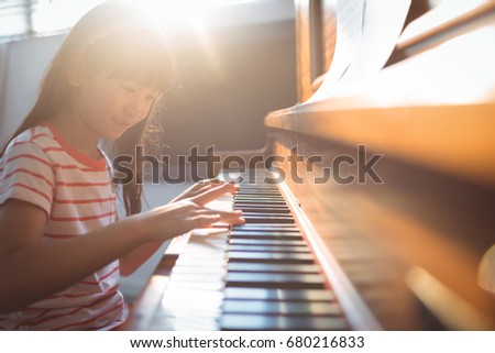 Smiling girl practicing piano in classroom at music school