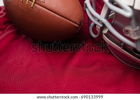 High angle view of American football and helmet on red jersey
