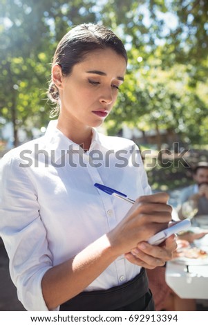 Waitress writing order on notepad in restaurant