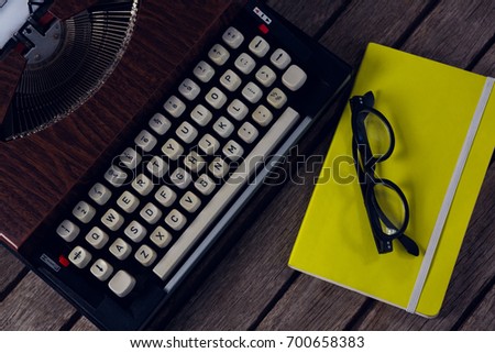 Overhead of vintage typewriter, diary and spectacles on wooden table