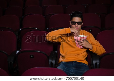 Man having popcorn while watching movie in theatre