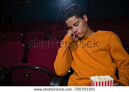 Bored man with popcorn sleeping in theatre