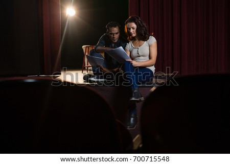 Actors reading their scripts on stage in theatre