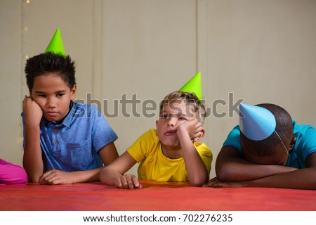 Bored children wearing party hat while sitting at table during birthday